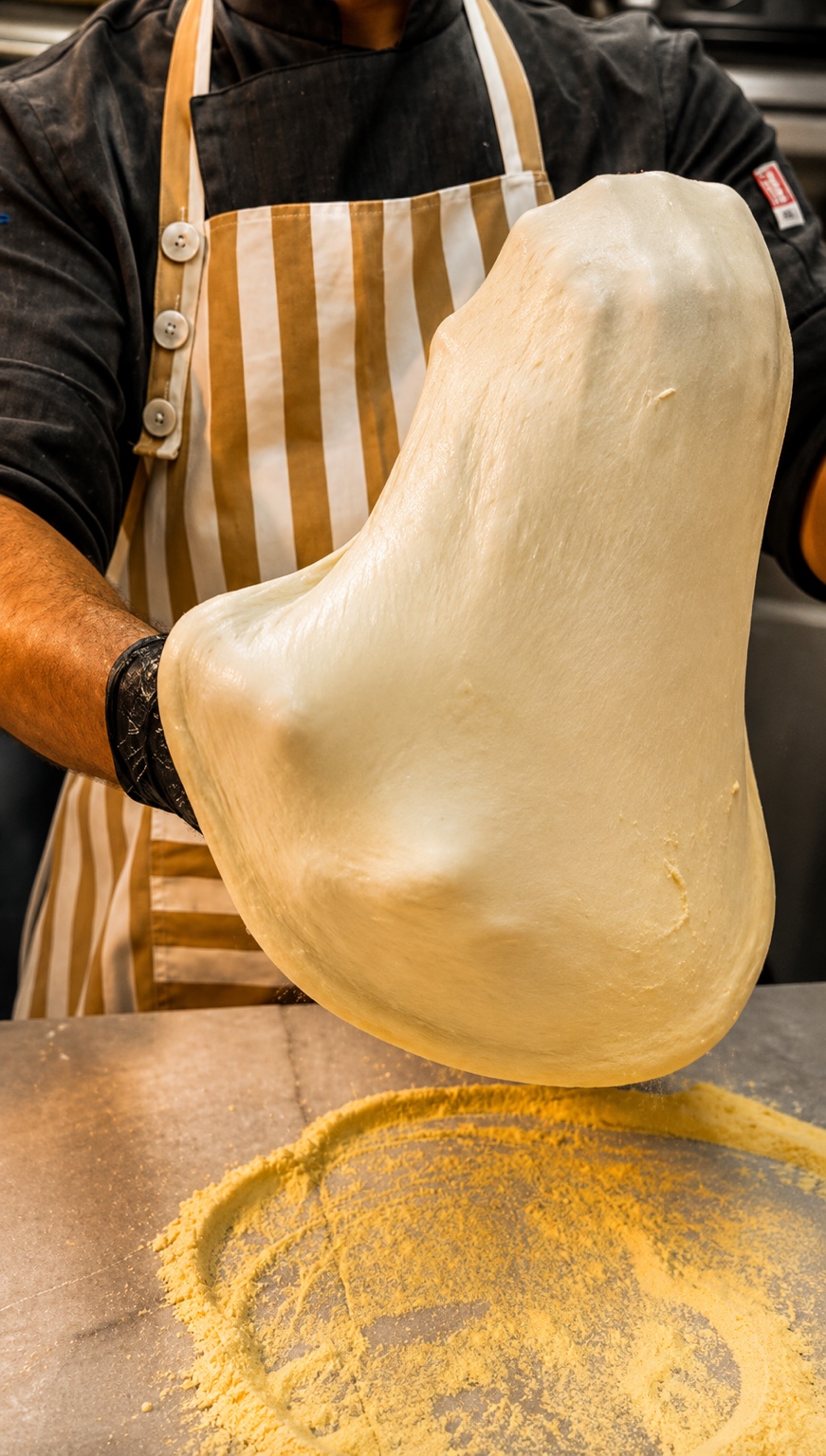 No1 Culinaria mutfağında şefin pizza hamurunu elle açması.